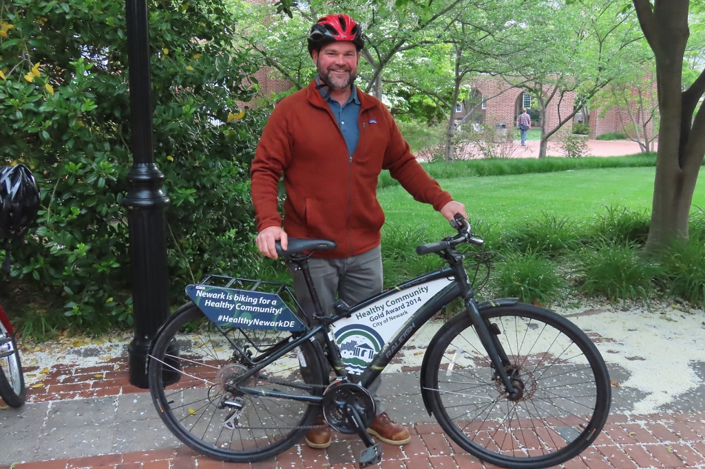Tim Filasky standing behind a staff bike with a rack and signs